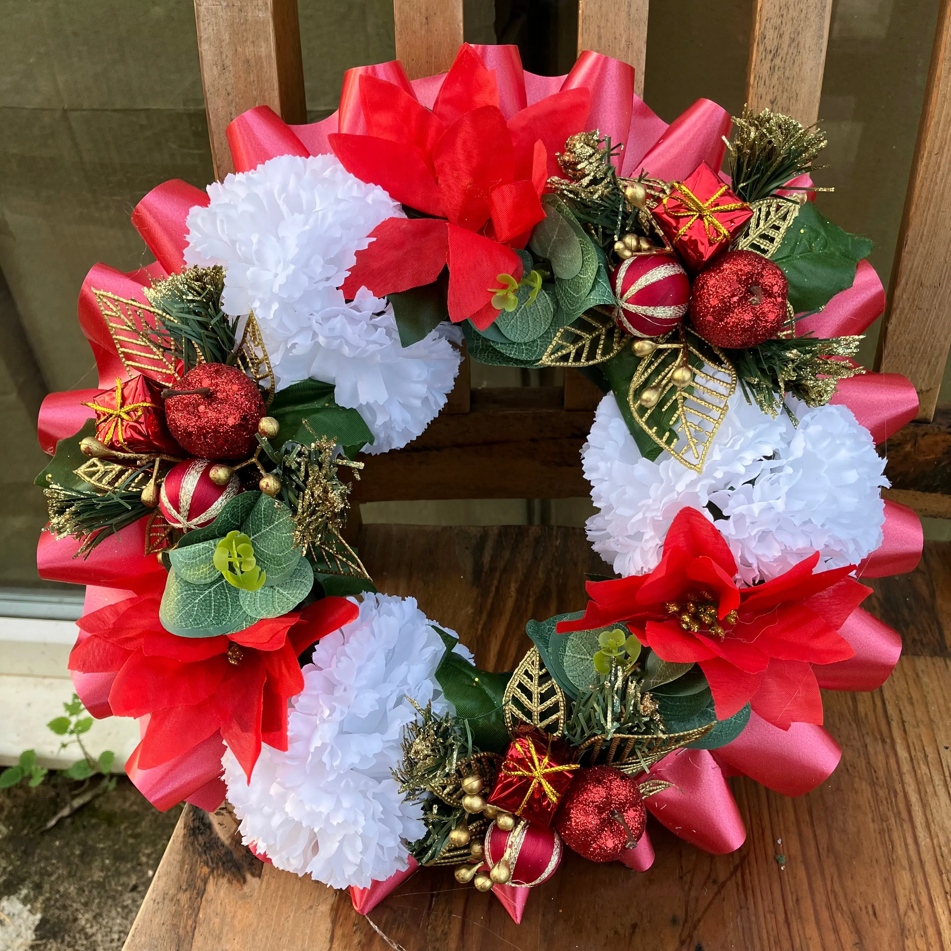 a memorial christmas wreath featuring parcels, carnations & poinsettia