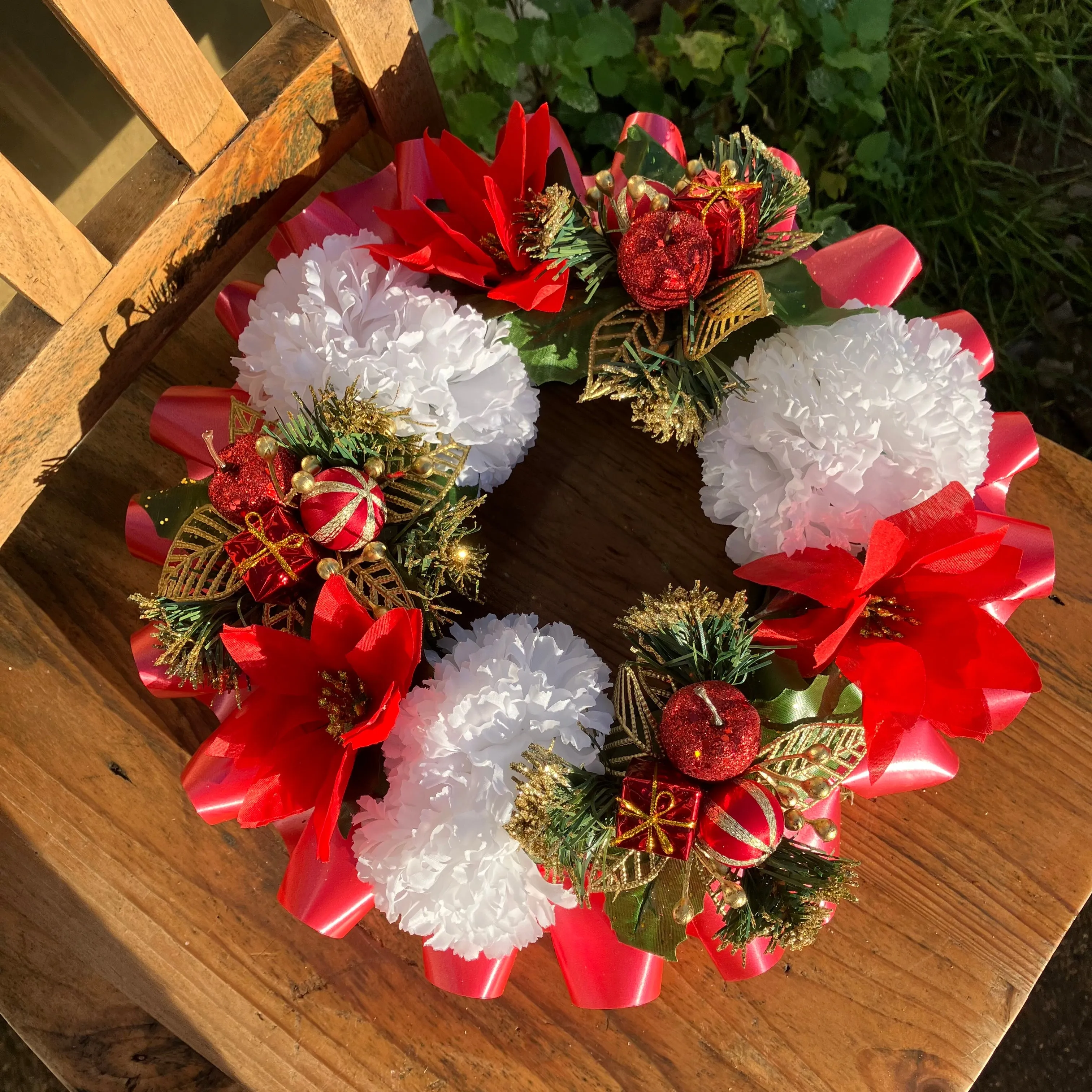 a memorial christmas wreath featuring parcels, carnations & poinsettia